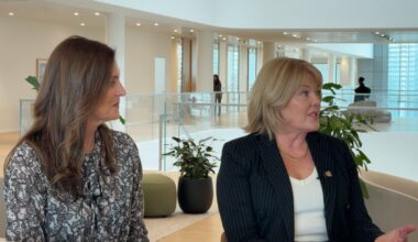 Two women with modern office backdrop.