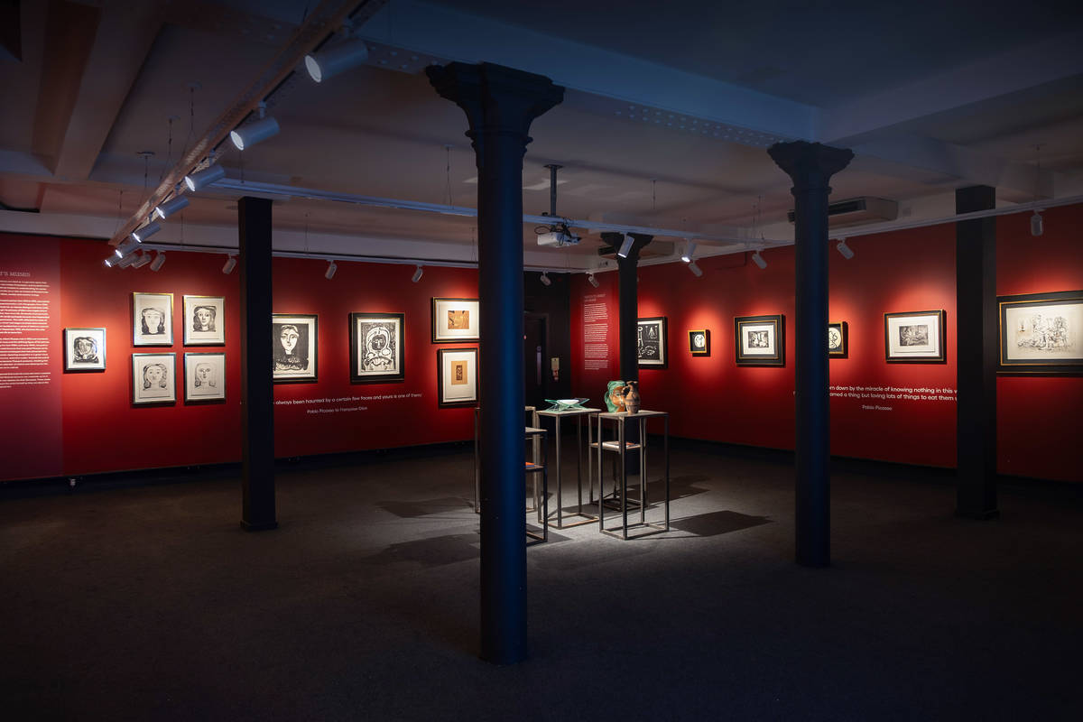 inside castle fine art gallery with red walls and pictures on walls and blue pillars