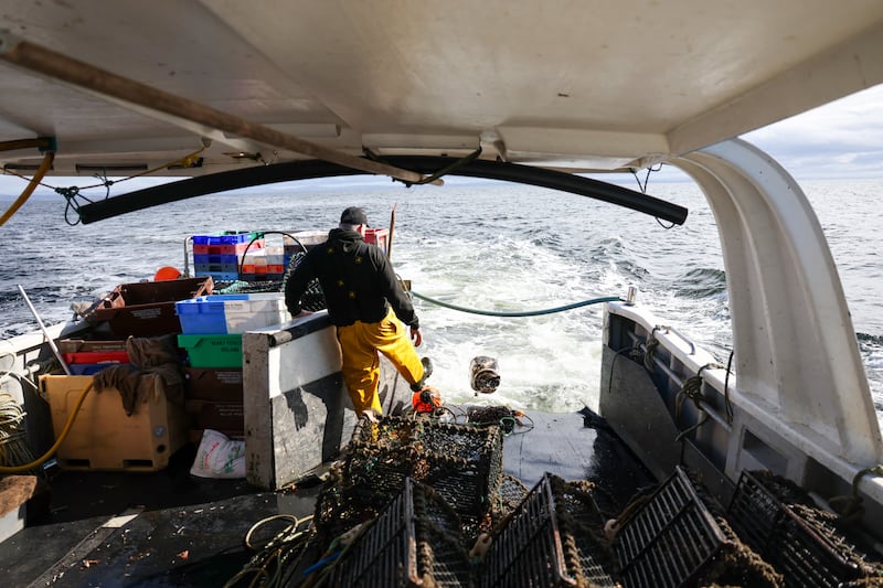 Menarry kicks a buoy off his boat. Photograph: Enda O'Dowd