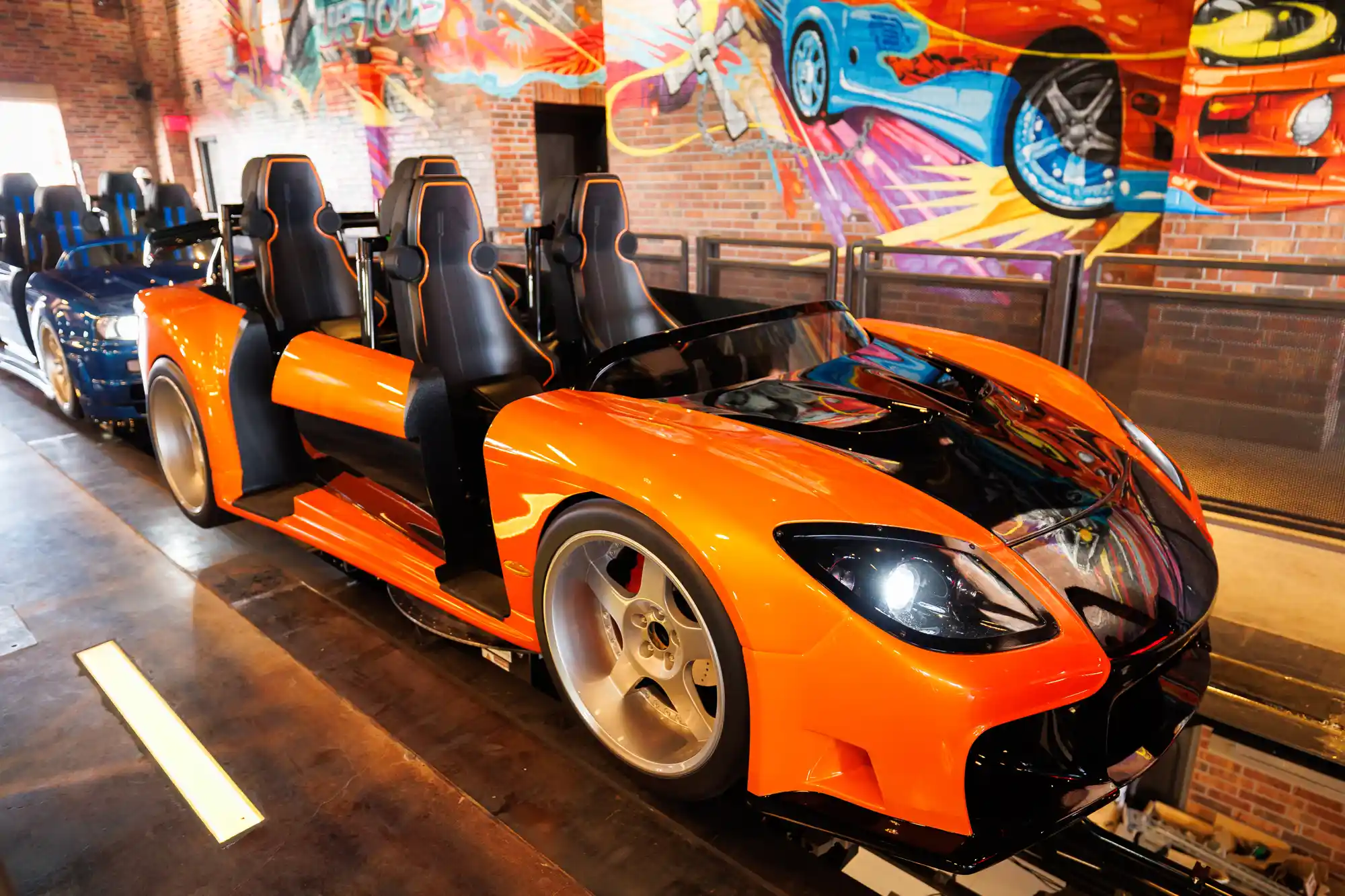 Sports car-themed orange coaster races down the track, with vibrant automotive murals decorating the Universal Studios Hollywood area.