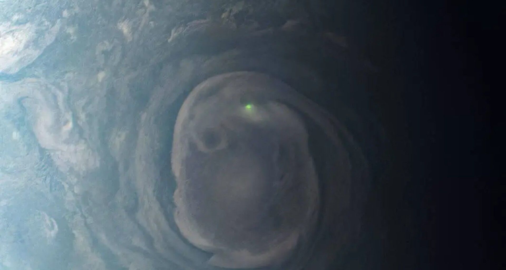 a bright dot of light in the center of a green and grey swirl