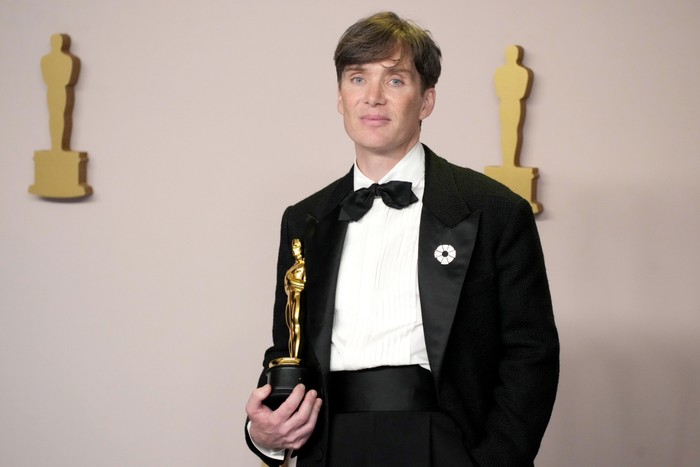 Cillian Murphy in evening jacket, white shirt and bow tie, holding an Academy Award
