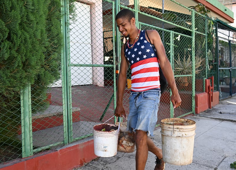 A man carries buckets down a street in Havana, Cuba. Photo by Yamil Lage/AFP via Getty Images