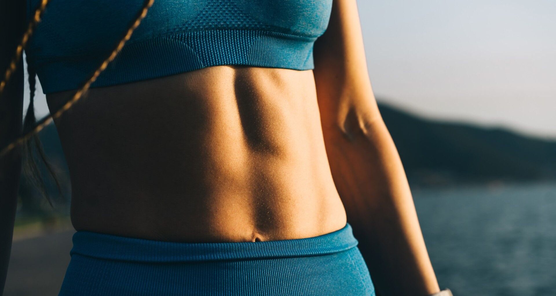 Woman's abs pictured close up in blue activewear