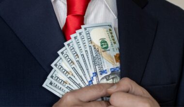 A rich man in a suit and tie counts US dollars in his hand and puts them in his pocket.