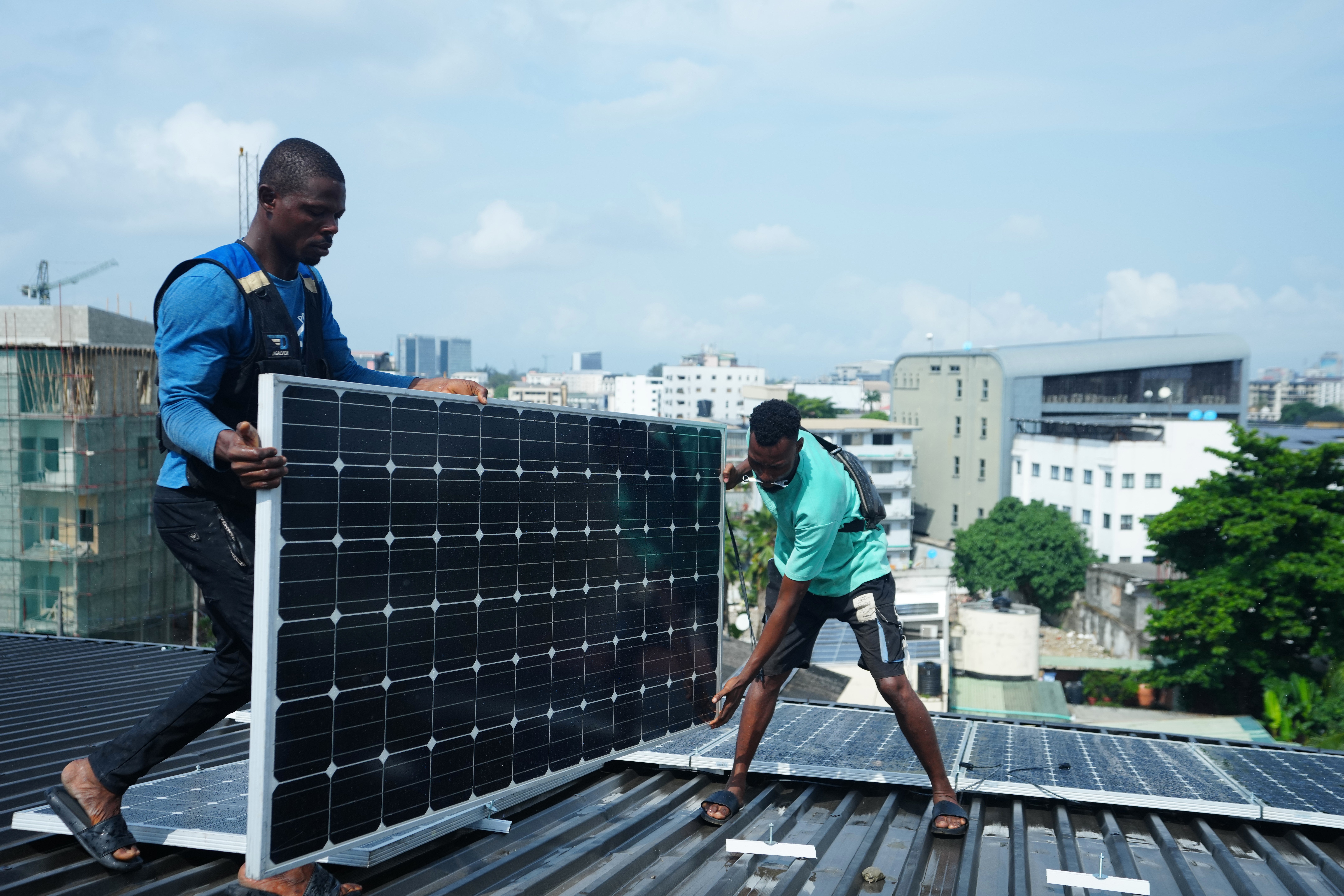 Workers install solar panels on a house roof.