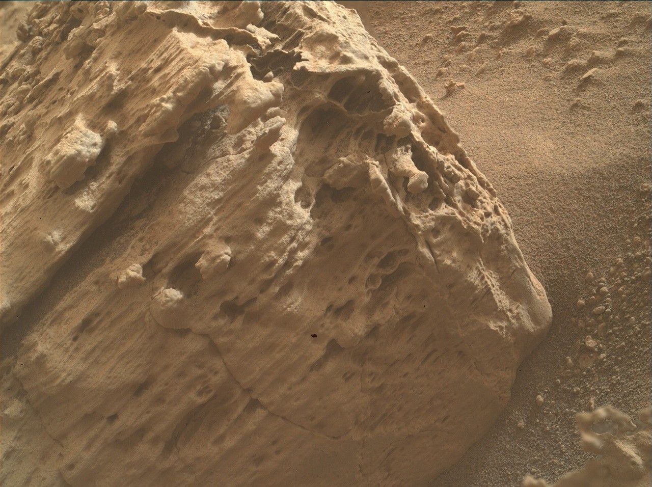 a mottled reddish-orange rock on a dusty surface of the same color