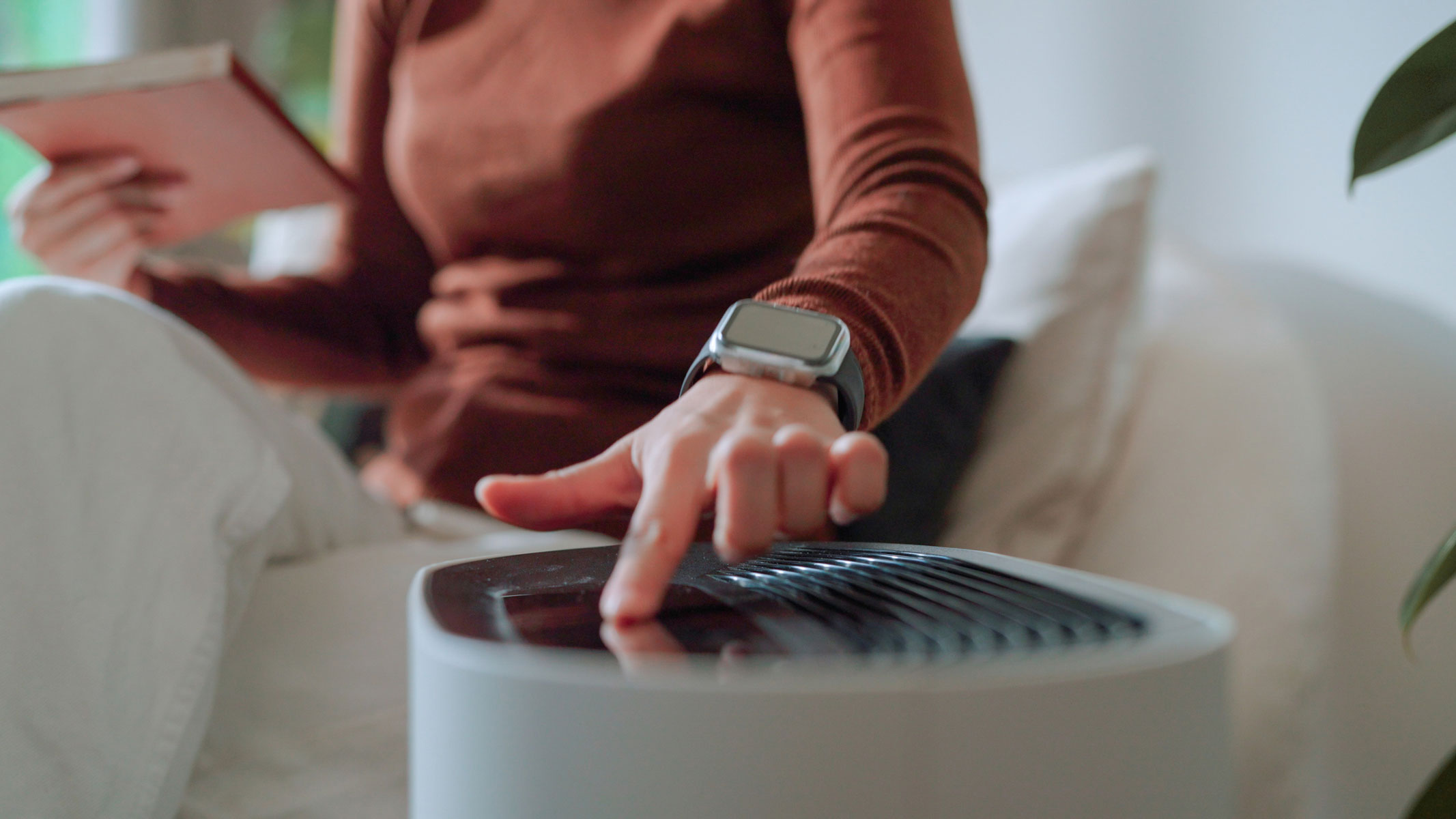 A close-up picture of a woman switching on an air purifier
