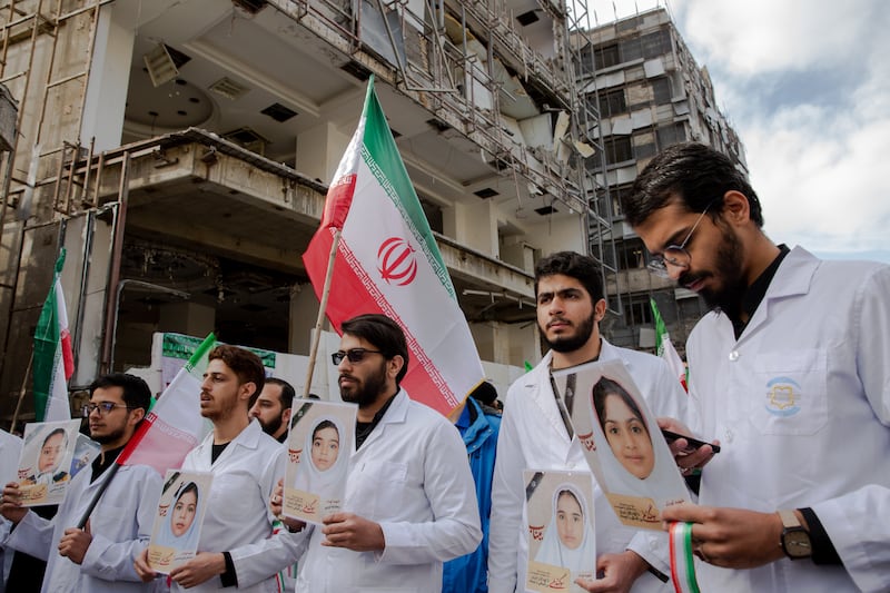 Iranian healthcare workers hold photos of schoolchildren killed in Minab during a demonstration outside the Gandhi Hospital in Tehran. Photograph: Arash Khamooshi/The New York Times
                      