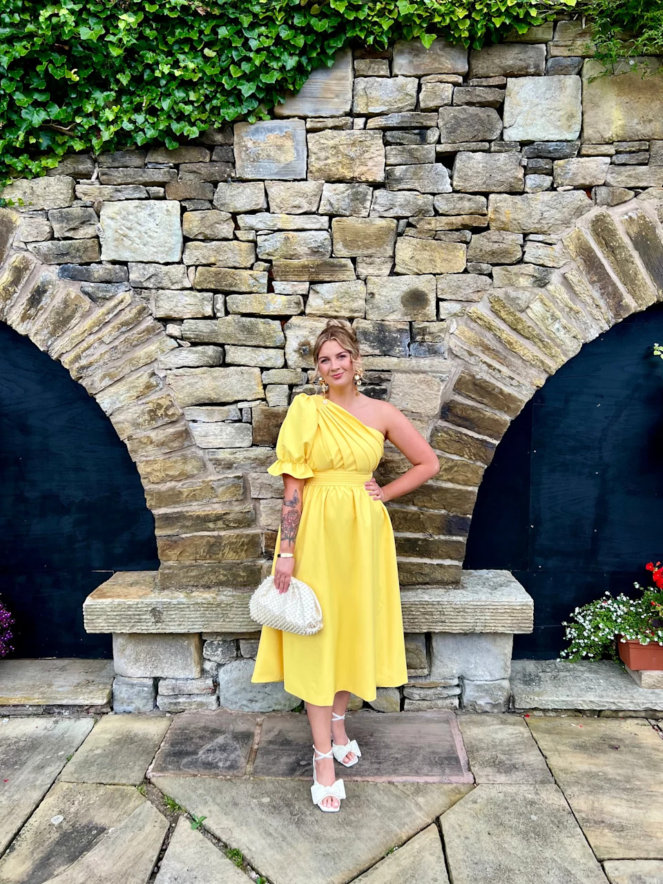 Katie in a yellow dress next to a stone wall