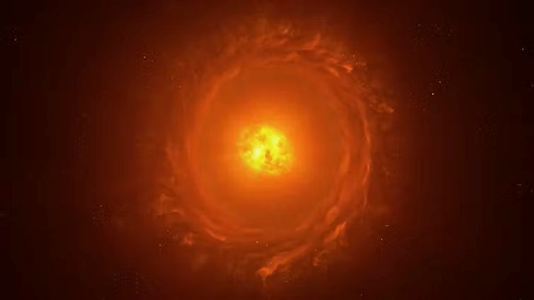 Biggest stars in the universe: Bright center in yellow with reddish debris in a disk around it, seen face on.