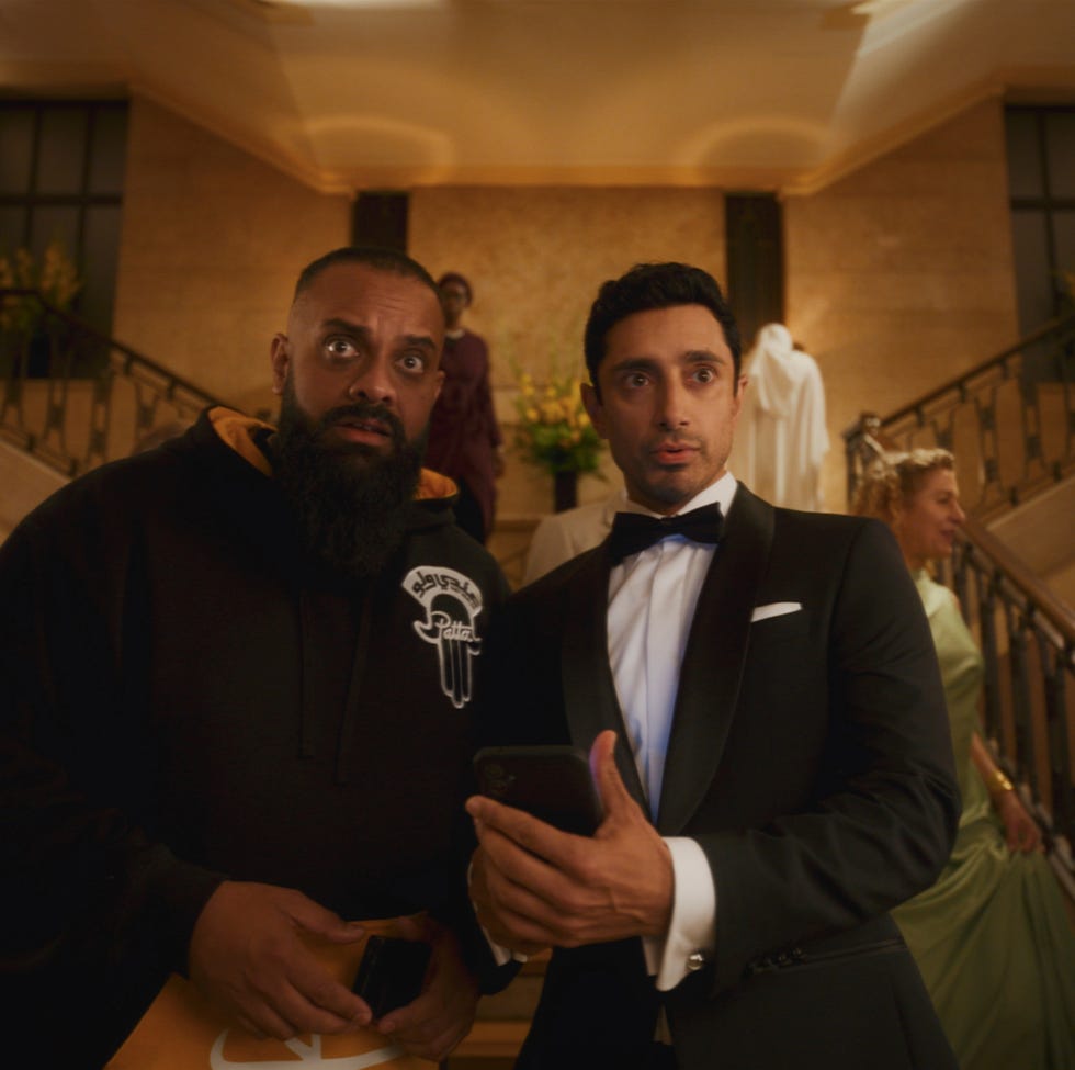 two individuals pose together in a formal setting with others in the background