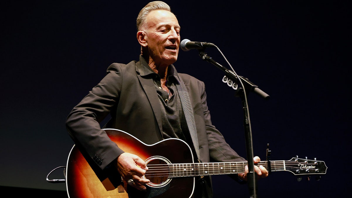 Bruce Springsteen holds guitar on stage