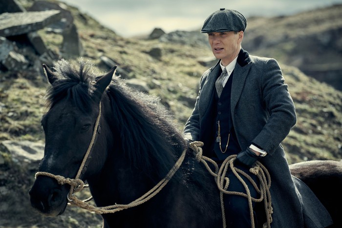 Cillian Murphy as Tommy Shelby in a dark coloured suit on top of a black horse.