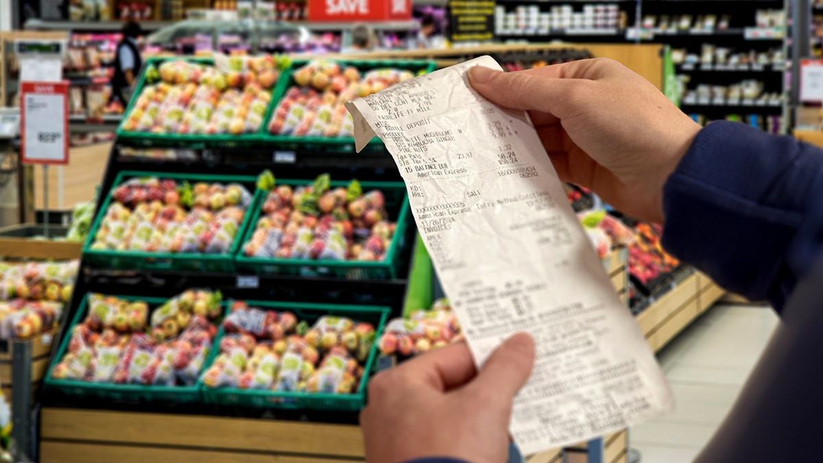 A receipt is held out in a grocery store.