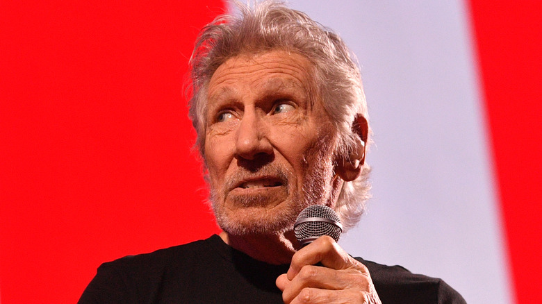 Roger Waters looking away uneasy and clutching microphone