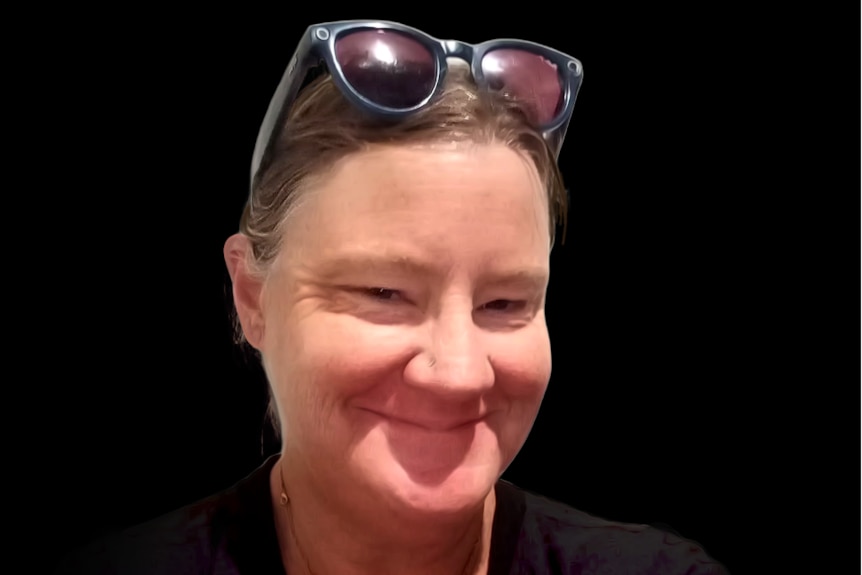 A smiling woman wearing a black-and-white striped sweater with dark-rimmed sunglasses propped on her head.