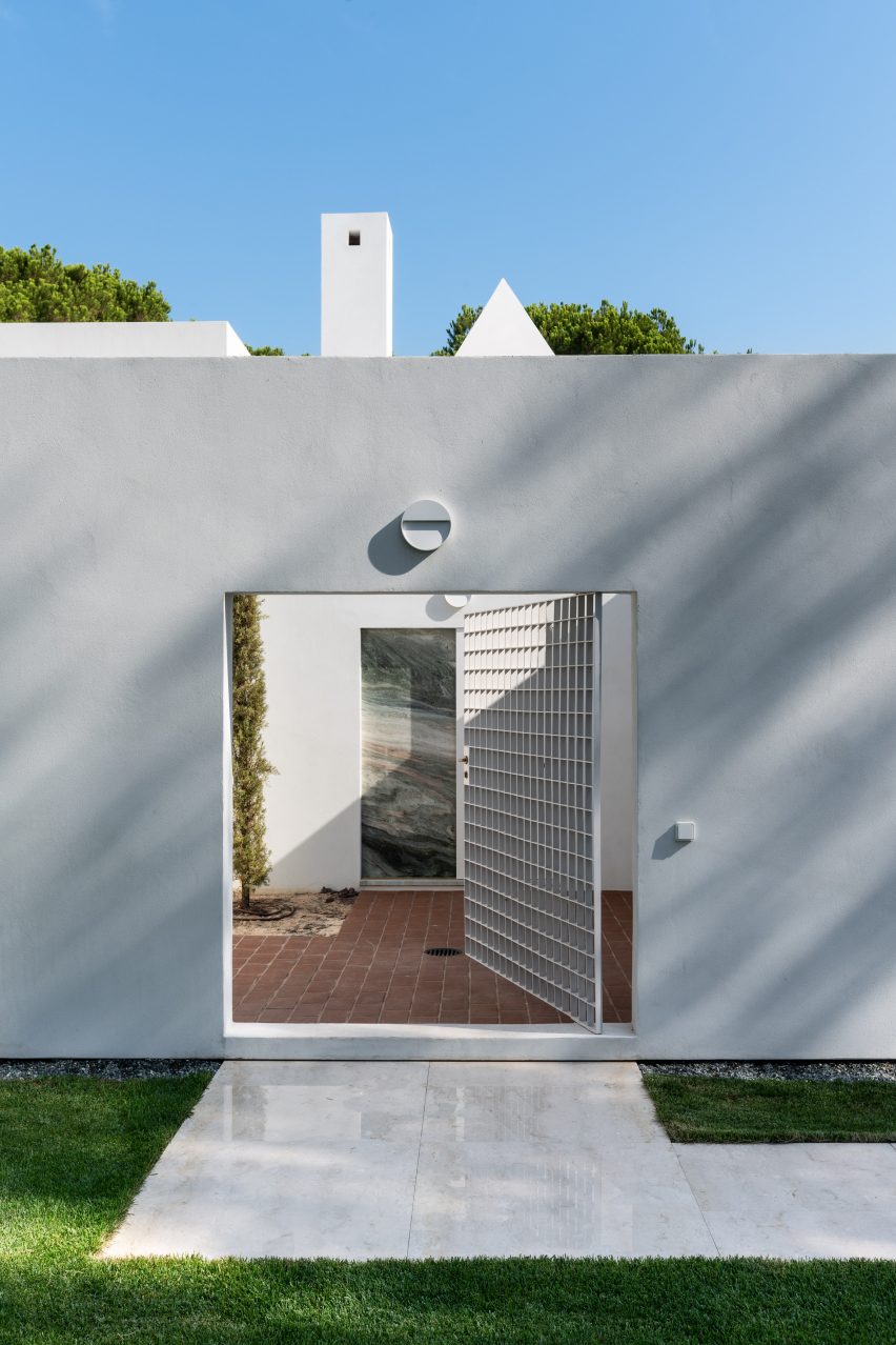 Entrance courtyard with white walls and metal gate at Quinta do Lago house by Eduardo Souto de Moura