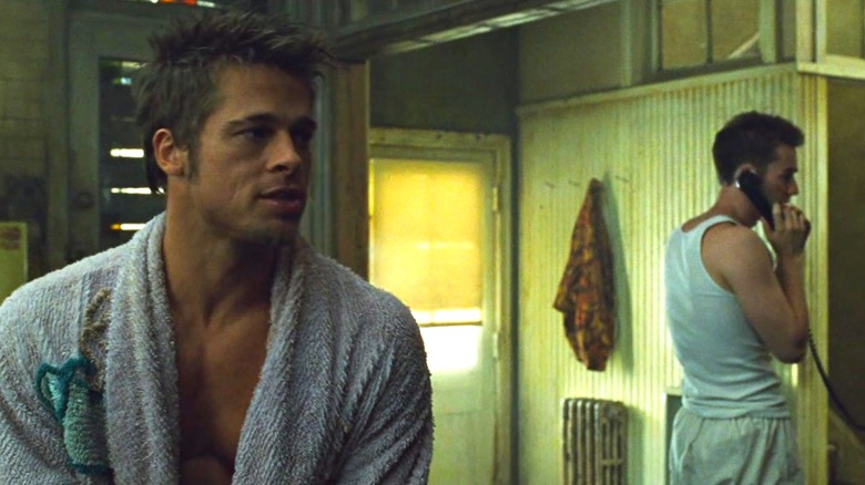 Brad Pitt as Tyler Durden in a bathrobe and Edward Norton as the Narrator on the phone behind him in Fight Club