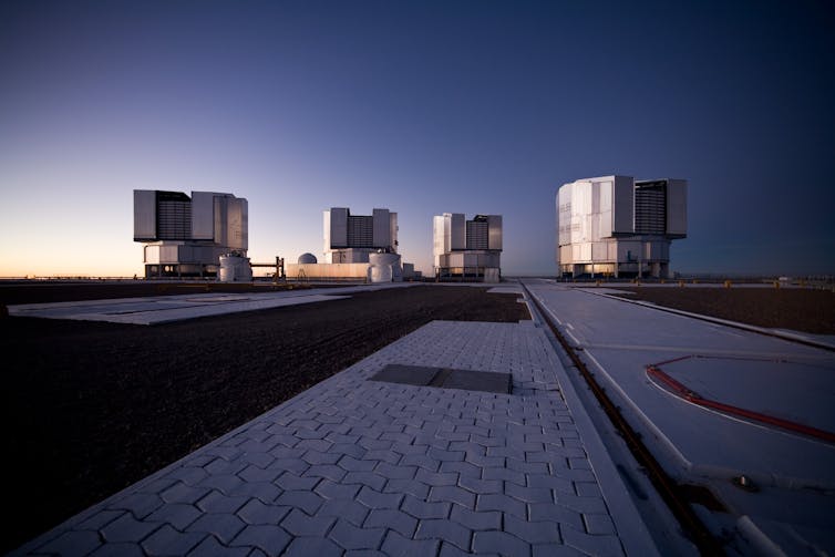 Four telescope units on a concrete platform.