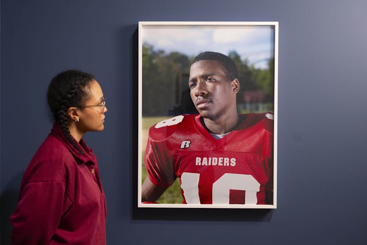 A woman looking at a portrait of an American football player.