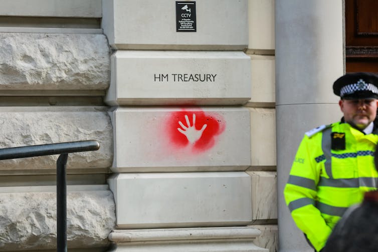 HM Treasury, red hand spray paint, policeman on guard