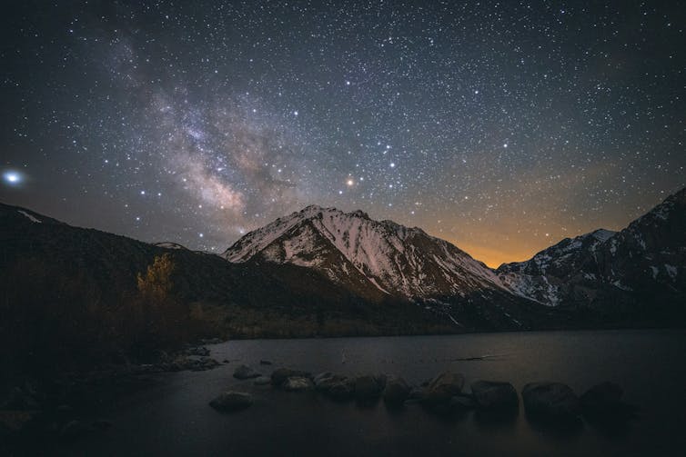 Image of the night sky over Convict Lake in California, with the sun setting behind a mountain.