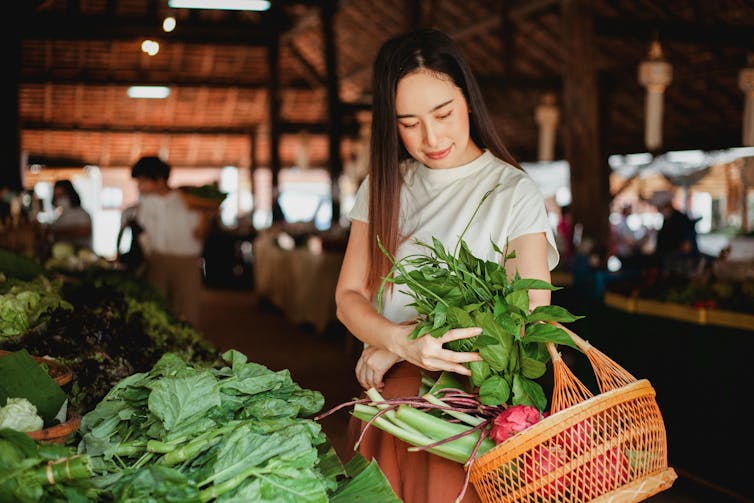 A woman buys fresh greens at a farmer's market.