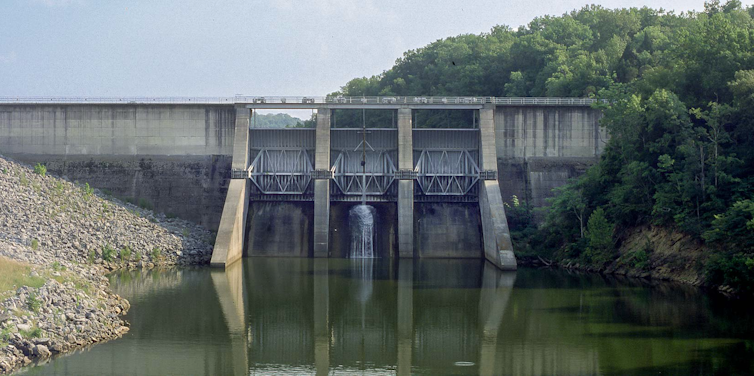A dam with a spillway, quiet water below, and trees on one side.