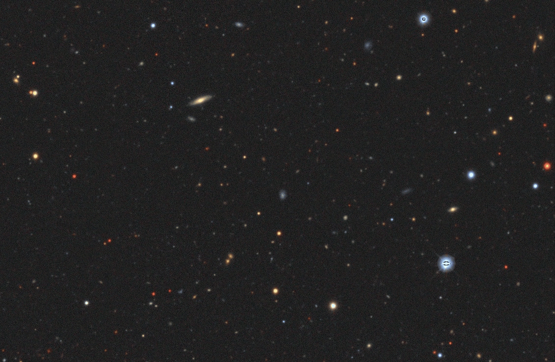 A dense star field in deep space with numerous stars and faint galaxies scattered against a dark background.