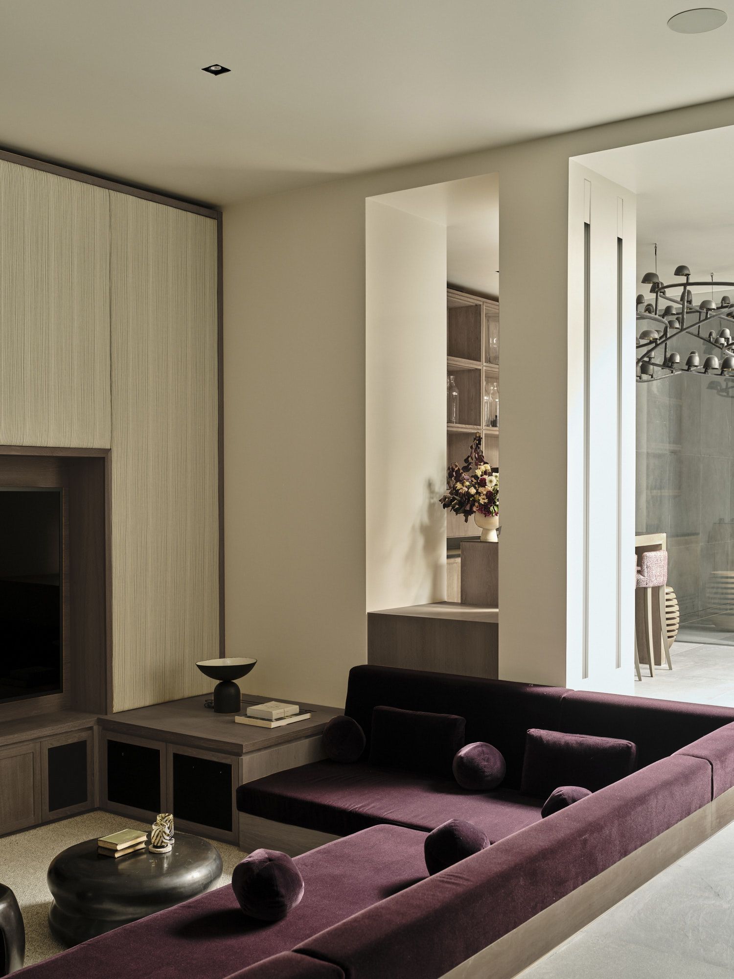 purple sofa conversation pit with cream walls, panelled walls with built-in joinery, round coffee tables