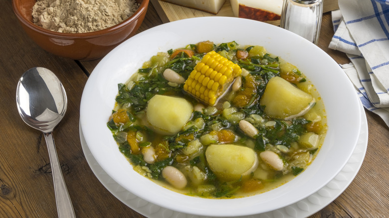a bowl of watercress soup with beans, potatoes, and corn
