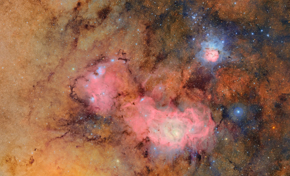A nebula with patches of pink, yellow and orange. There's an array of blue stars peeking out from the background.