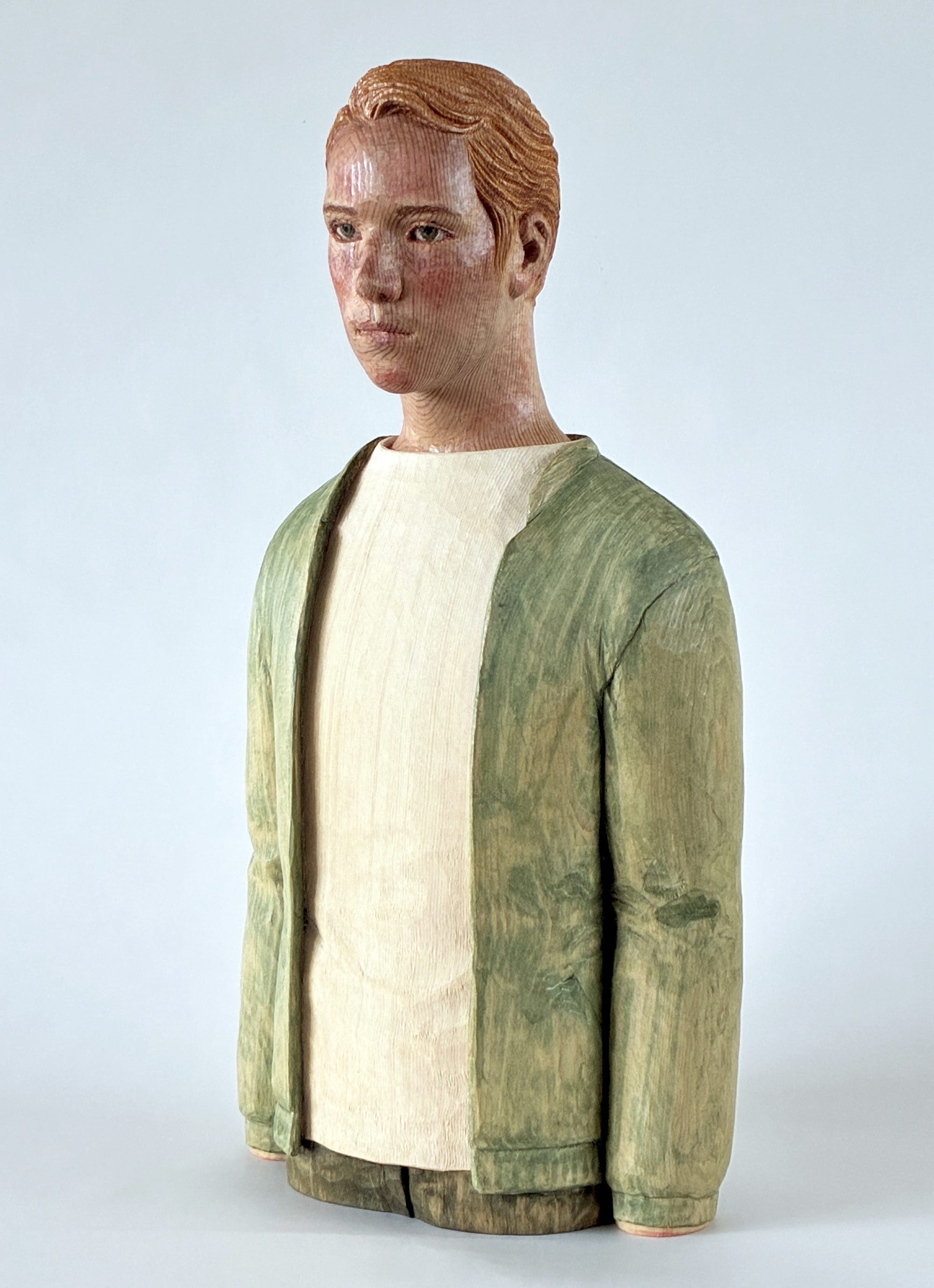 A figurative, painted wood sculpture of a young man in three-quarter profile by Shinsuke Inoue