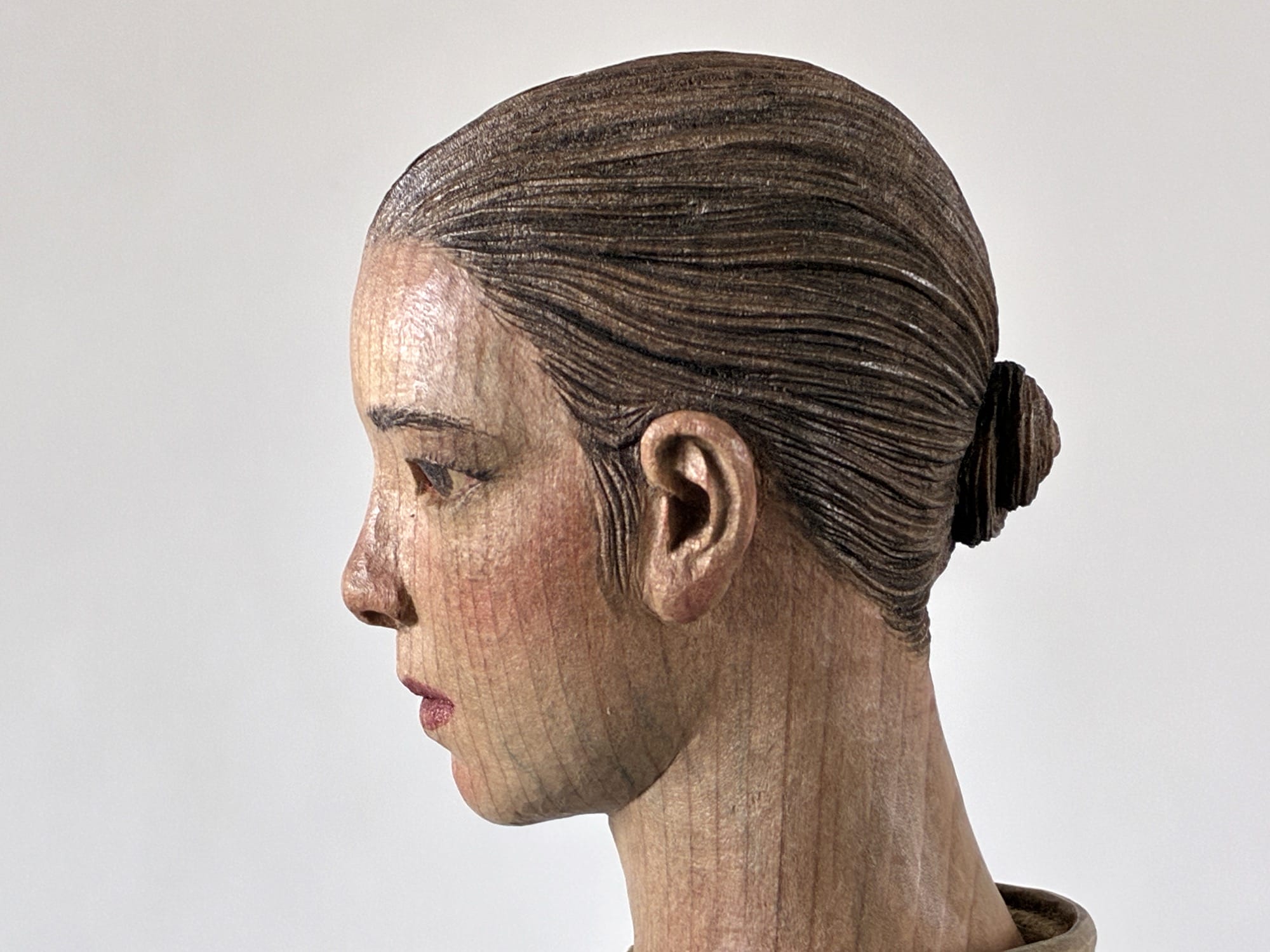 A figurative, painted wood sculpture by Shinsuke Inoue in profile