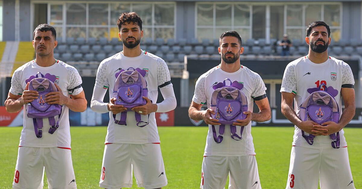 Iran wear black armbands and hold schoolbags during national anthem before match