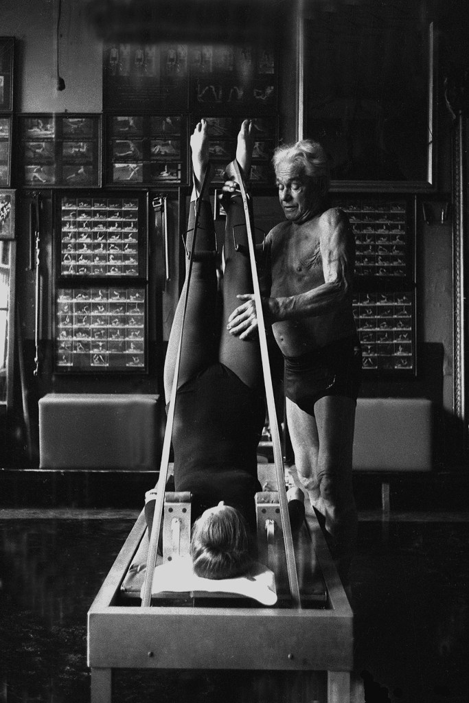 Joseph Pilates, founder of the Pilates exercise method, helps a client through an exercise routine in his 8th Avenue studio.