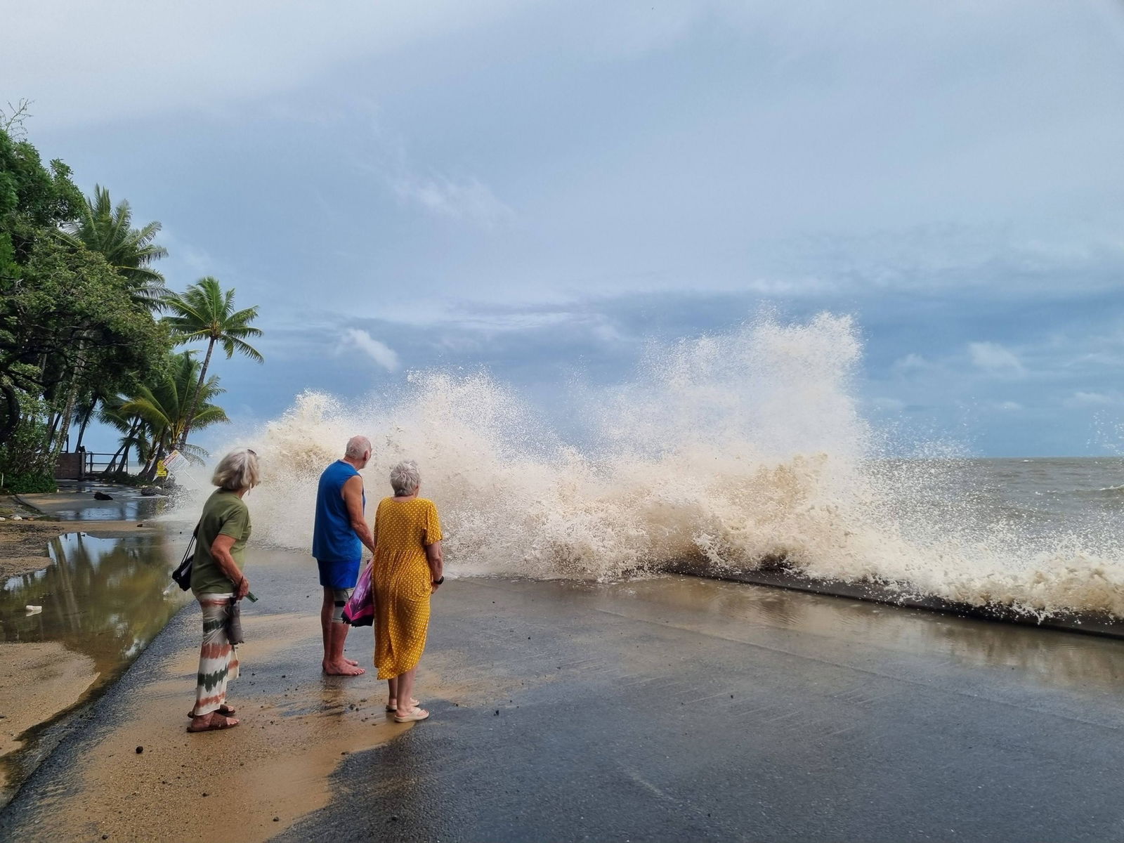a large wave breaking on a beach next to people