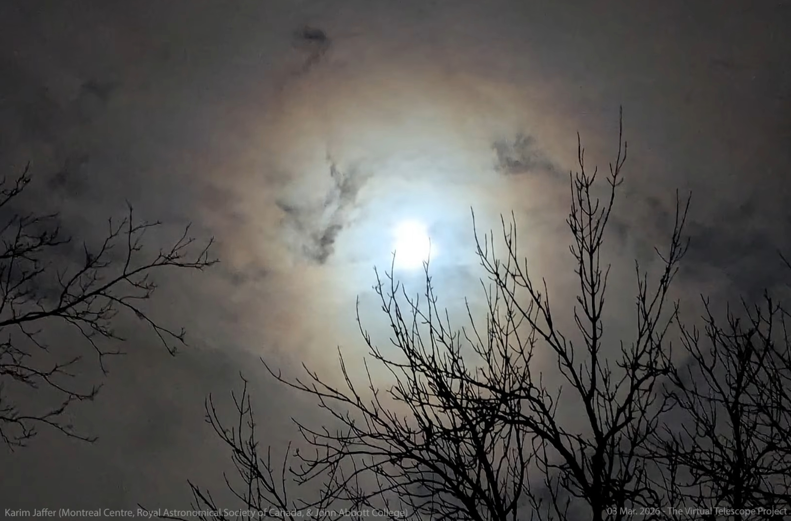 screenshot from virtual telescope livestream showing a bright moon against a cloudy sky