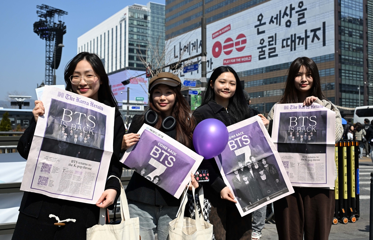 BTS fans pose with The Korea Herald's BTS special edition print at Gwanghwamun Square in Seoul, Saturday. (Lee Sang-sub/The Korea Herald)