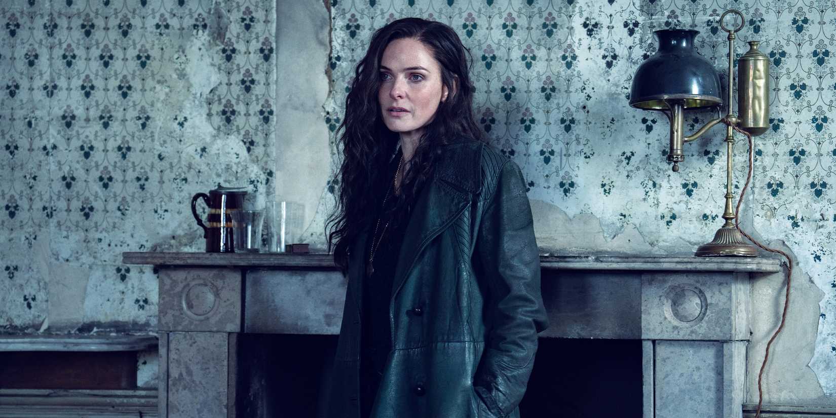 Kaulo stands in front of a fireplace with her hands in the pockets of her coat.