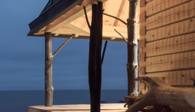 Charred tree trunks support Puusauna by Jaakko Torvinen