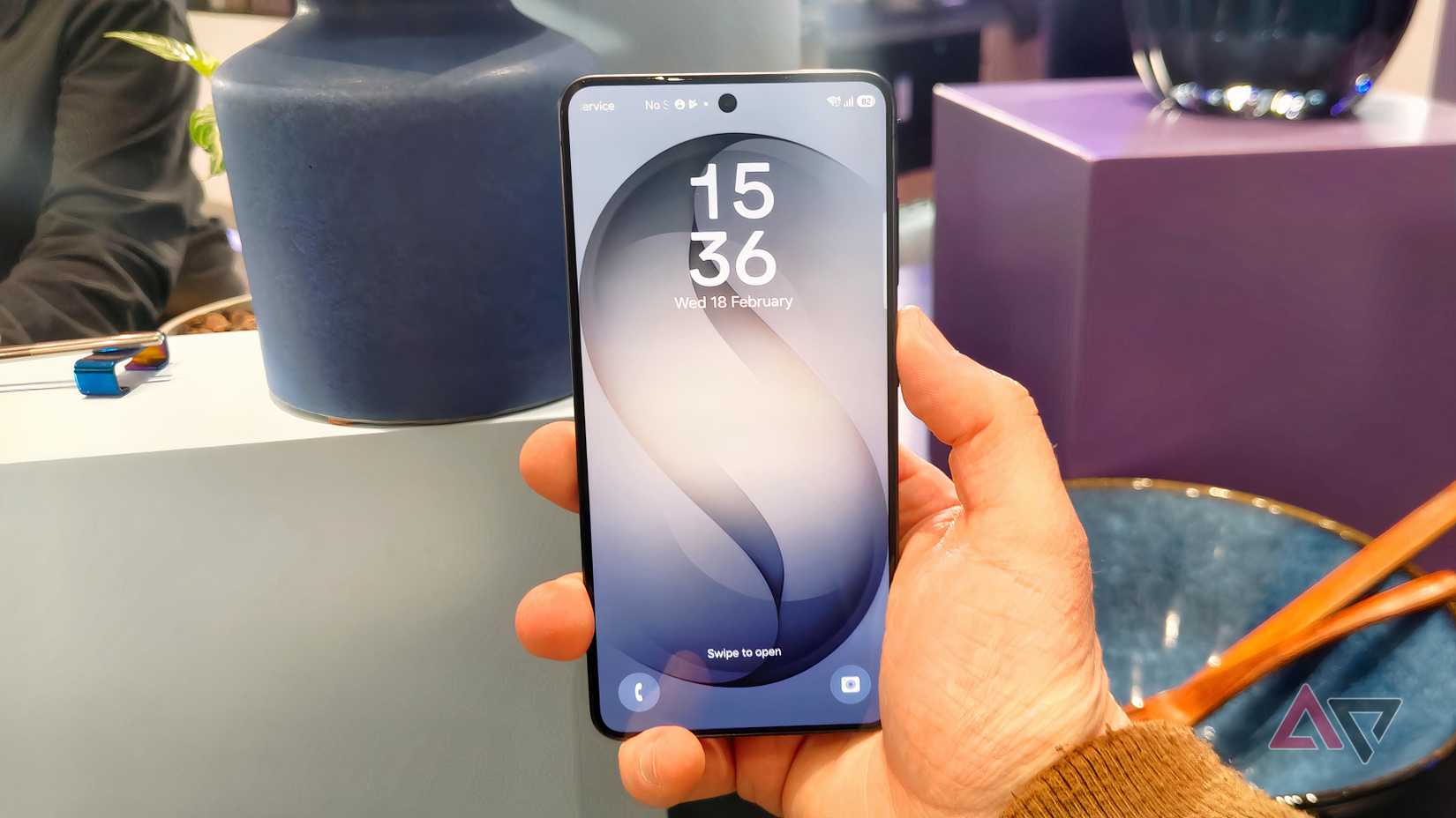 The Samsung Galaxy S26 in a man's hand, showing the lock screen.