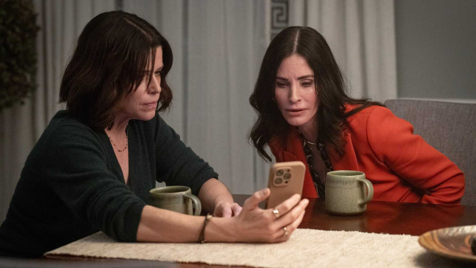 Sidney and Gale staring at a phone screen with concern in Scream 7