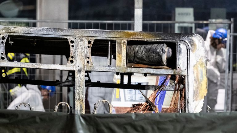 Investigators examine the charred shell of the bus. Pic: AP