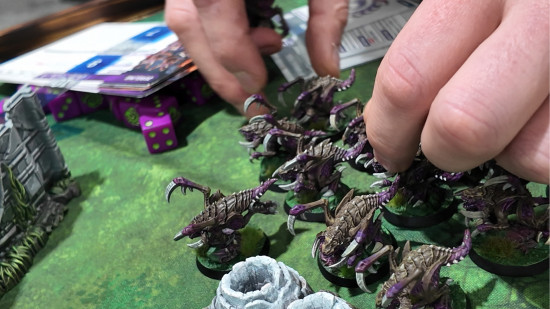 A player moving Zergling figures in the from the Starcraft Tabletop Miniatures Game