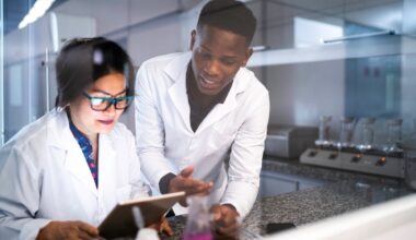 Researchers in white coats discuss trial results in a lab.
