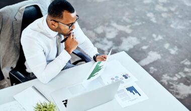 An analyst is sitting at a desk, thinking while reviewing a document.