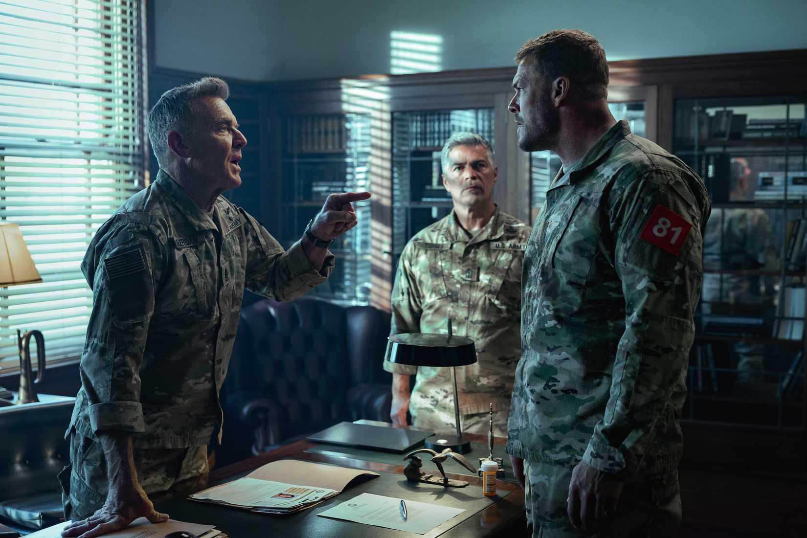 Two Army officers (Dennis Quaid, Esai Morales) chew out sergeant 81 (Alan Ritchson) in a military office in War Machine