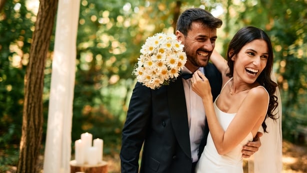 Young bride and groom are laughing and hugging during their wedding ceremony in the woods